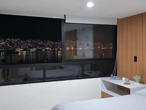 a bedroom with a view of a city at night at Departamento frente a bahía con hermosa vista in Acapulco
