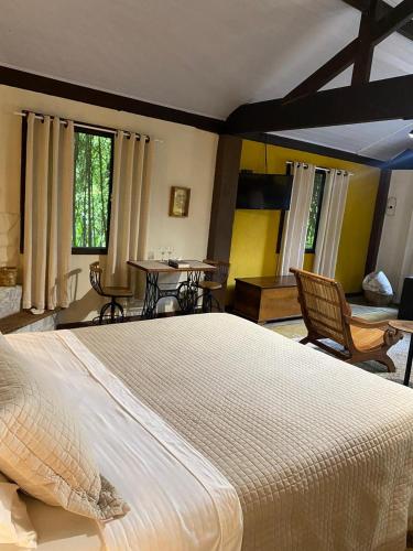 a bedroom with a large bed and chairs and windows at Havilá Arara Azul in Nova Friburgo