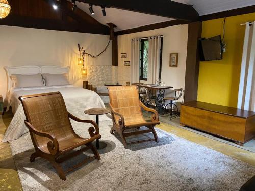 een slaapkamer met een bed, twee stoelen en een tafel bij Havilá Arara Azul in Nova Friburgo