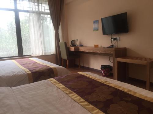 a hotel room with two beds and a desk with a television at Holly's Hostel in Chengdu