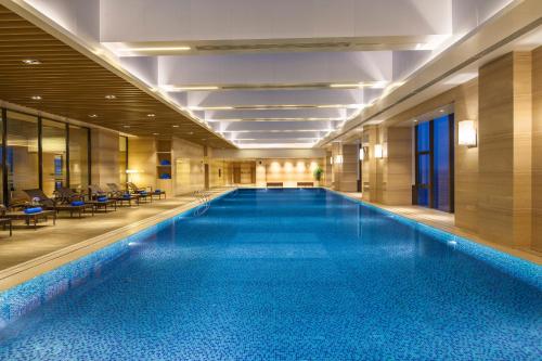 a large swimming pool in a hotel lobby at Somerset Aparthotel Xindicheng Xi'an in Xi'an
