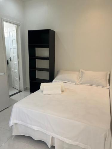 a bedroom with a large white bed with a black cabinet at Suíte privativa in Boa Vista