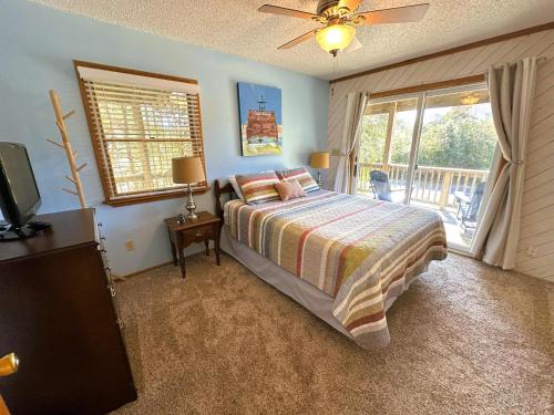 a bedroom with a bed and a television and a balcony at D112-Happy Go Ducky in Duck