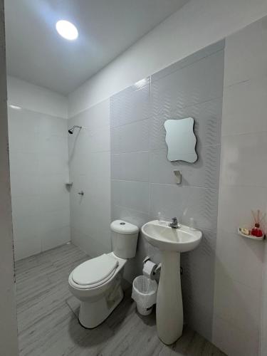 a white bathroom with a toilet and a sink at Hotel Casa Colonial Moñitos in Moñitos
