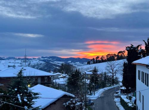 un tramonto invernale con la neve sui tetti delle case di Ampio appartamento centro storico a Montalto Pavese