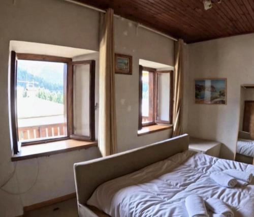een slaapkamer met een bed en twee ramen bij Rium Dolomiti - Casa con Vista in Pieve di Cadore