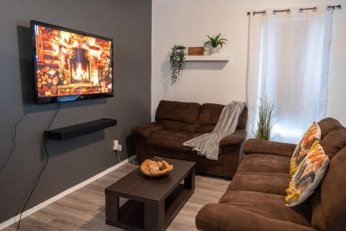 a living room with a couch and a tv on a wall at Rare Cozy Home near Downtown WPG - Free Parking in Winnipeg