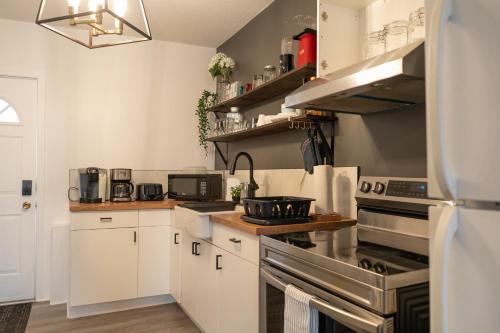 a kitchen with white cabinets and stainless steel appliances at Rare Cozy Home near Downtown WPG - Free Parking in Winnipeg
