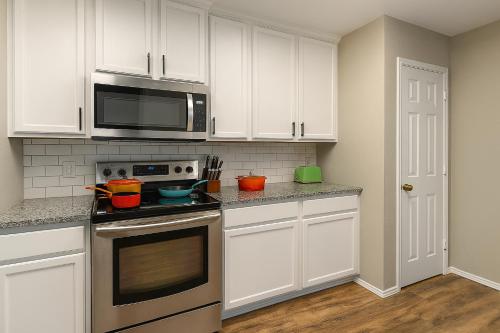 eine Küche mit weißen Schränken, einem Herd und einer Mikrowelle in der Unterkunft Crew Stay Sleeps 16 Work, Cook, Play & Relax in Navo