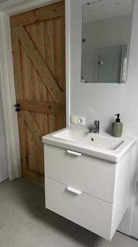 a white bathroom sink with a mirror and a door at Benbijdokkum in Driesum