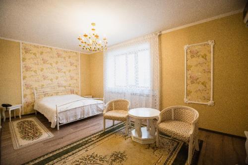 a bedroom with a bed and a table and chairs at Park EmpAir Hotel in Pavlodar
