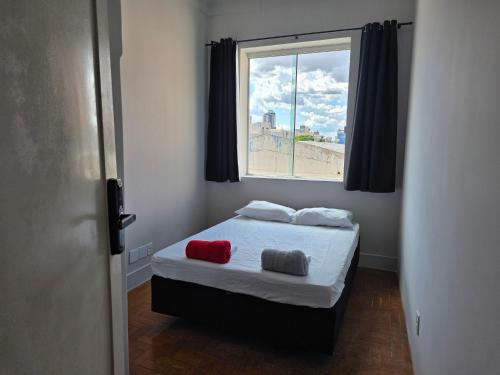a bedroom with a bed with two pillows and a window at Cerrado Hostel in Goiânia