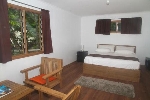 ein Schlafzimmer mit einem Bett, einem Stuhl und einem Fenster in der Unterkunft Evis Resort at Nggatirana Island in Halisi