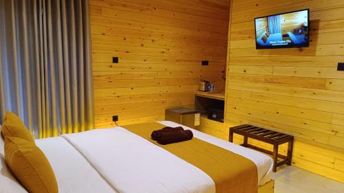 une chambre avec un lit et une télévision à écran plat dans l'établissement Wood Chalets Ella, à Ella