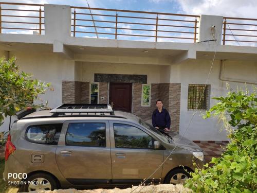 een man die met zijn auto voor een huis staat bij Peacock Abode Farm in Bangalore