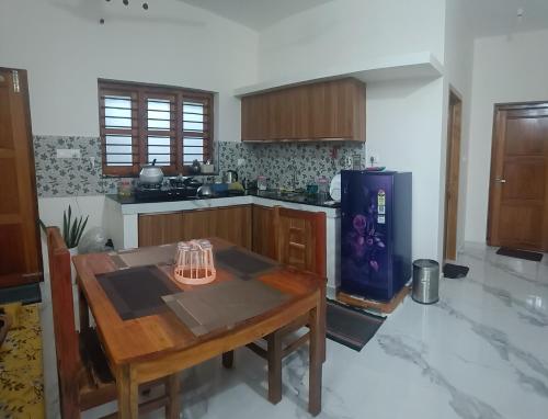 eine Küche mit Holztisch und Kühlschrank in der Unterkunft Sandora Home Stay in Varkala