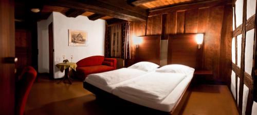 een slaapkamer met een bed en een rode stoel bij Gasthof Waldgericht in Dornstetten