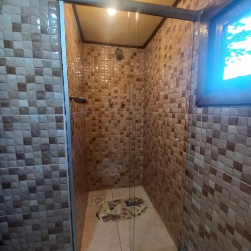 a bathroom with a shower with a glass door at Estalagem Refúgio do Capão in Cambará