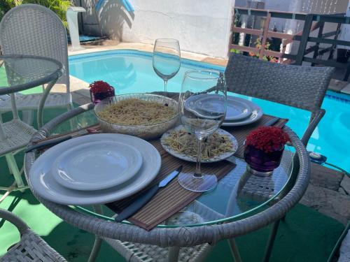 a table with plates and wine glasses next to a pool at Pousada Prime Center in Pipa