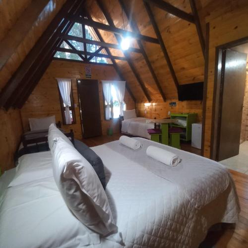 a bedroom with a large white bed in a attic at Estalagem Refúgio do Capão in Cambará