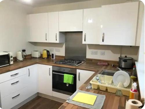 een keuken met witte kasten en een spoelbak bij NG Property in Glasgow