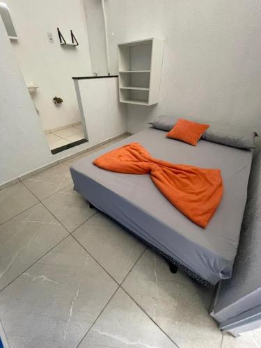 a bed in a room with an orange blanket on it at Hostel Mariah in Cabo Frio