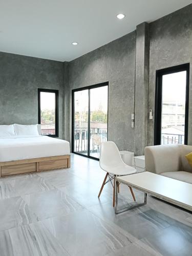 a bedroom with a bed and a couch and a table at Loft Life Pool villa in Ban Huai Yai