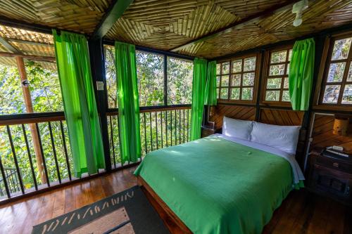 - une chambre avec des rideaux verts et un lit dans l'établissement Bellavista Cloud Forest Lodge & Private Protected Area, à Tandayapa