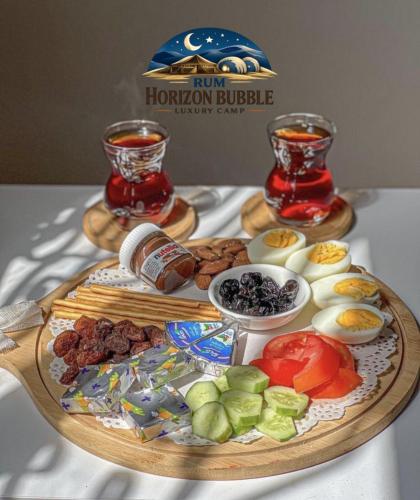 a platter of food on a table with two drinks at RAM HORlZON BUBBLE LUXURY CAMP in Wadi Rum