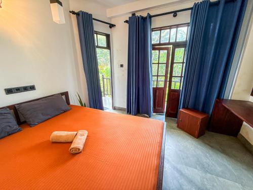 a bedroom with a large orange bed with blue curtains at Black Lantern in Matara