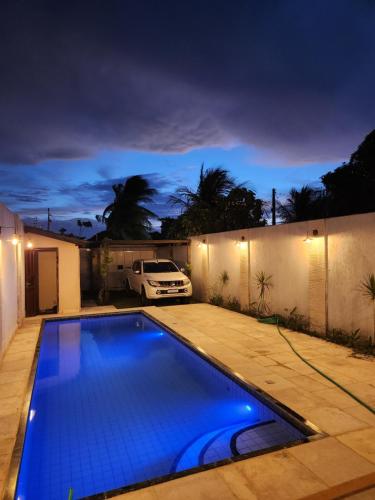 a swimming pool at night with a car parked in a driveway at Dúplex Lagoa in Paracuru