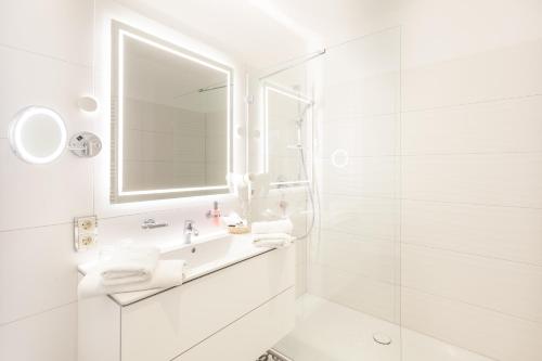 ein weißes Badezimmer mit Waschbecken und Spiegel in der Unterkunft freustil Boutique Hotel in Binz