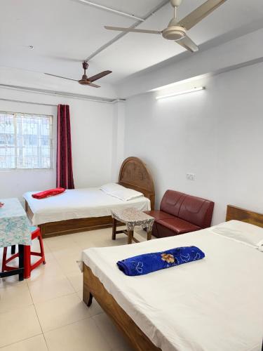 una stanza con tre letti, un divano e un soffitto di Hotel Rose International a Dhaka