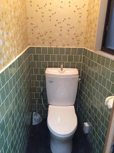 a bathroom with a white toilet in a green tiled wall at Hanakiya in Kyoto