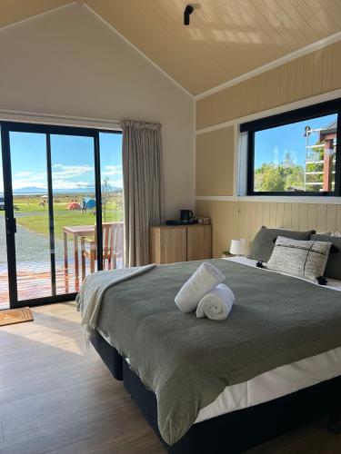 a bedroom with a large bed with a large window at The Barn Cabins & Camp in Marahau
