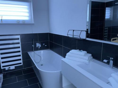 een badkamer met een bad, een wastafel en een spiegel bij Bungalow KONI in Annaberg im Lammertal