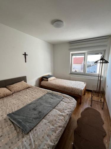 een slaapkamer met 2 bedden en een kruis aan de muur bij Apartman Marija in Kupres