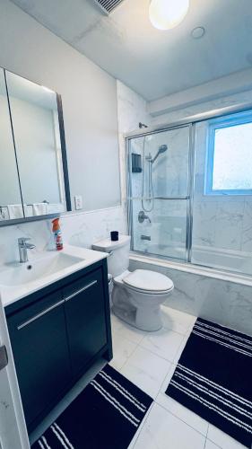 a bathroom with a toilet and a sink and a shower at Explore Rooms JFK in Locust Manor