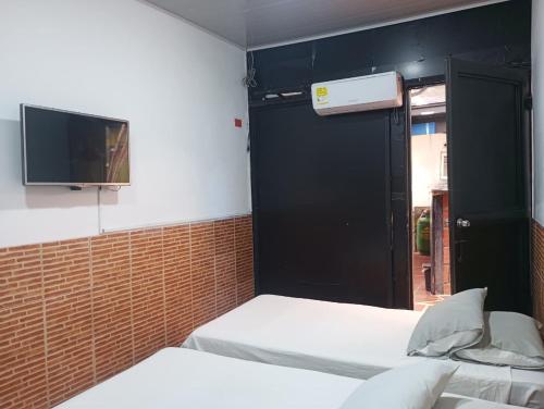 a room with two beds and a tv on the wall at Hotel KAMELLON in Estación El Salto