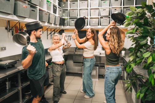 a group of people standing in a kitchen holding pots and pans at Mad Monkey Potts Point in Sydney