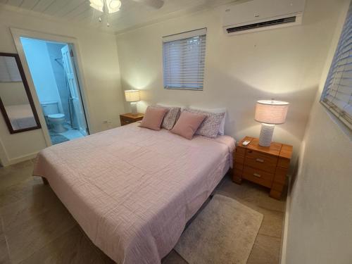 - une chambre avec un lit doté d'oreillers roses et d'une fenêtre dans l'établissement Tickled Pink, à Harbour Island