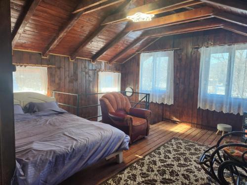 a bedroom with a bed and a chair and windows at Cabana Maria in Olăreşti