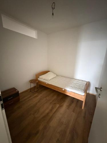 een kleine slaapkamer met een bed en een houten vloer bij Wohnung Magdalene in Größing