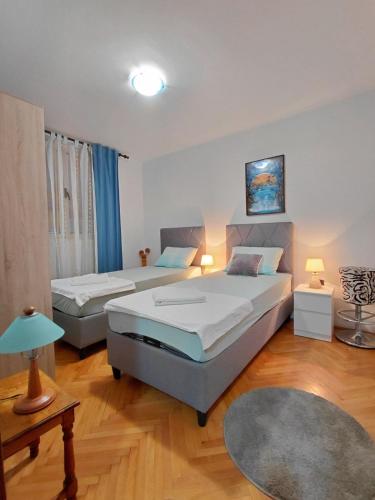 a bedroom with two beds and a rug at Apartment Maruni in Šušanj