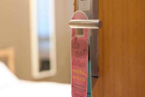 a pink doorhandle with a sign that says dog is not intelligent at Room@Doze in Nonthaburi