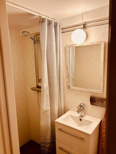 a bathroom with a sink and a shower with a mirror at Kaj's Cabin in Listerby