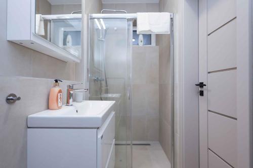 a white bathroom with a shower and a sink at Lúka Palúdzka in Liptovský Mikuláš
