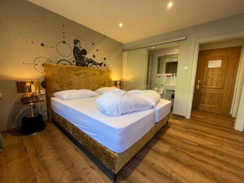 een slaapkamer met een groot bed met witte lakens bij Landhotel Lindenhof in Feld am See