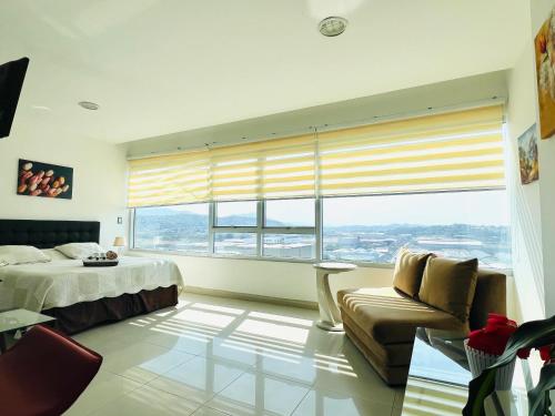 a bedroom with a bed and a couch and a large window at Luxury City Suites in Guayaquil