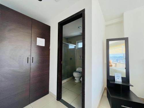a bathroom with a toilet and a mirror at Luxury City Suites in Guayaquil